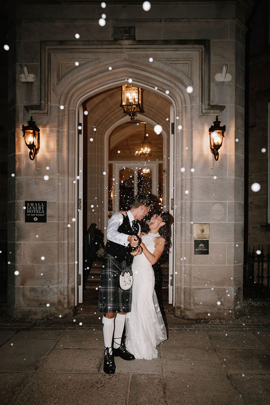 Nighttime champagne spray bride and groom outside Crossbasket Castle